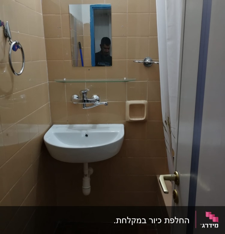 כיור עם ברז ומראה בחדר אמבטיה קטן